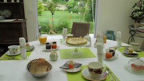 A breakfast table with a variety of items including a pie, beverages, and a basket of bread. - Bed and Breakfast 'Entre Mer Et Terre - Chambre' with Shared Garden and Wi-Fi (Bazenville)