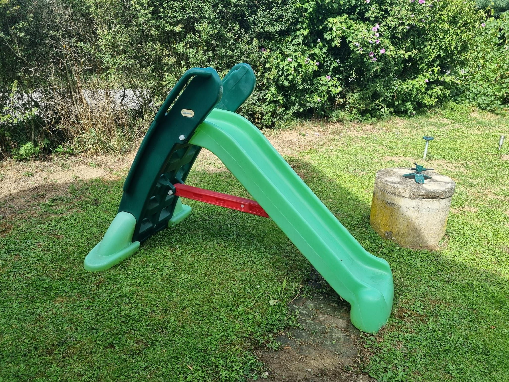 A playground with a green slide and a red climbing structure.