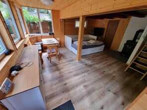 Una cabaña de madera compacta con comedor, cama y pequeña cocina.