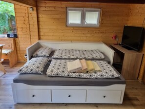 Un dormitorio de cabaña de madera con una cama, un televisor y una ventana.