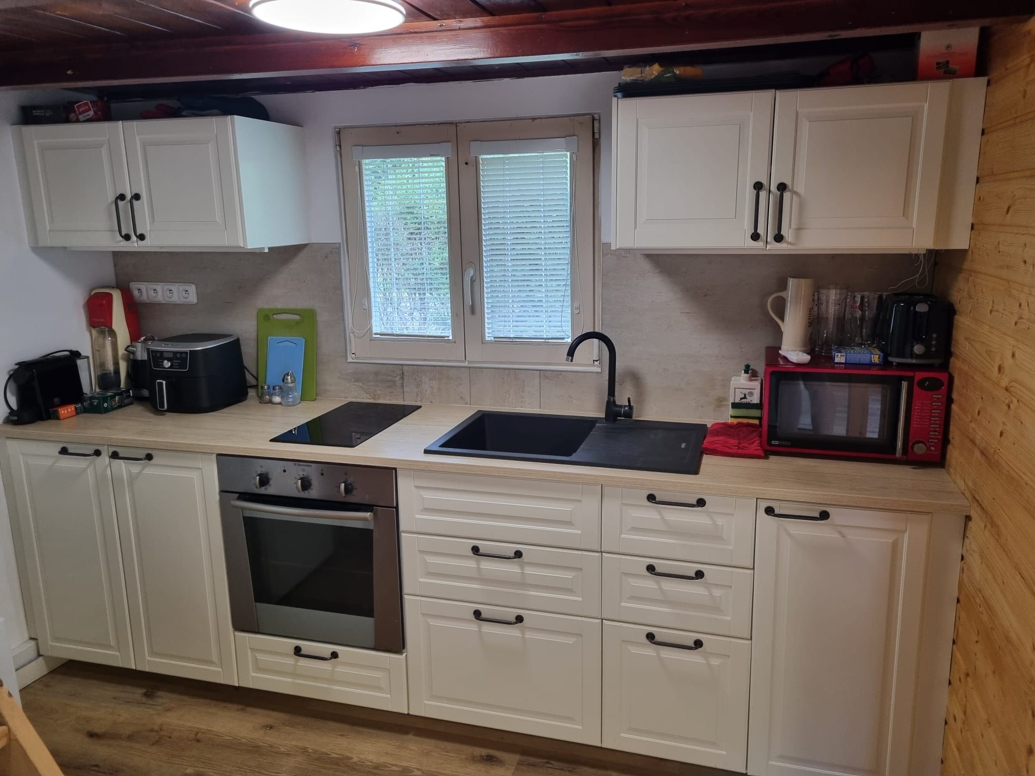 A compact kitchen with a built-in oven, a sink, and a microwave.