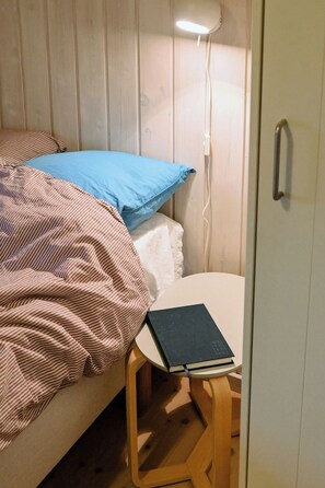 A bedroom with a bed, a bedside table with a book, and a wall-mounted light. - Summer house with two terraces near Rødhus Strand (Pandrup)