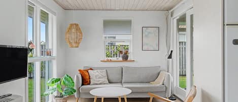 A modern living room with a grey sofa, a round coffee table, and a television.