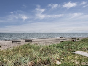 Una platja amb tres bancs i un vaixell a la riba.