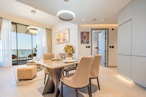 A modern dining area with a round table, chairs, and a vase of flowers. - Sky Level 1BR with Balcony Overlooking the Canal, Short Drive from Burj Khalifa (Dubai)