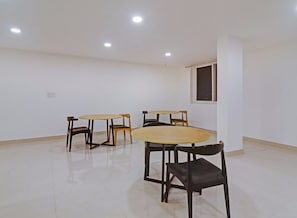 A room with four tables and chairs, a window, and recessed ceiling lights. - Townhouse Che Sigma (Hyderabad)