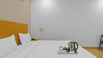 Habitación de hotel con una cama, una mesita de noche, una bandeja con cafetera, tazas y un hervidor.
