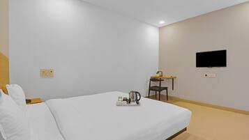 Une chambre d’hôtel équipée d’un lit, d’un bureau, d’une chaise, d’une télévision et d’un plateau avec une bouilloire et des tasses.