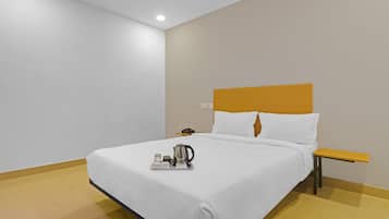 Ein Hotelzimmer mit einem Bett, einem Nachttisch mit Telefon und einem Tablett mit Wasserkocher und Tassen.