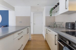 A modern kitchen with white cabinets, a grey countertop, and a built-in oven. - Flatzy - Prime City Apartment 2 Baths Sleeps 6 (Merseyside)
