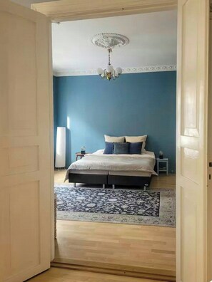 A bedroom with a bed, a nightstand, a floor lamp, and a patterned rug. - Moody vintage apartment in Oslo (Oslo)