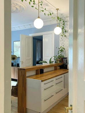 A kitchen with a wooden countertop, white cabinets, and hanging pendant lights. - Moody vintage apartment in Oslo (Oslo)