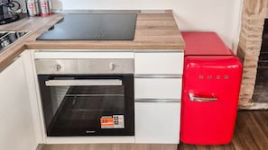 A compact kitchen with a built-in oven, a red refrigerator, and a wooden countertop. - Apartments 1889 - Cozy Studio Apartment Just a Few Meters from the Sea in Porto Sant'Elpidio (Porto Sant`Elpidio)