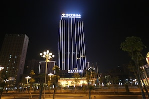Un edificio de hotel alto con detalles de iluminación vertical y un letrero en un idioma extranjero en la parte superior.