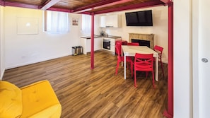 Un espacio habitable compacto con comedor, kitchenette y televisor montado en la pared.