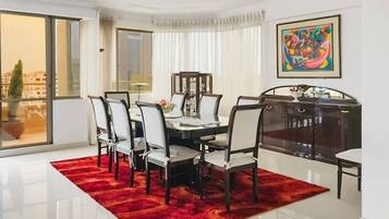 A dining area with a glass table, chairs, and a red rug.