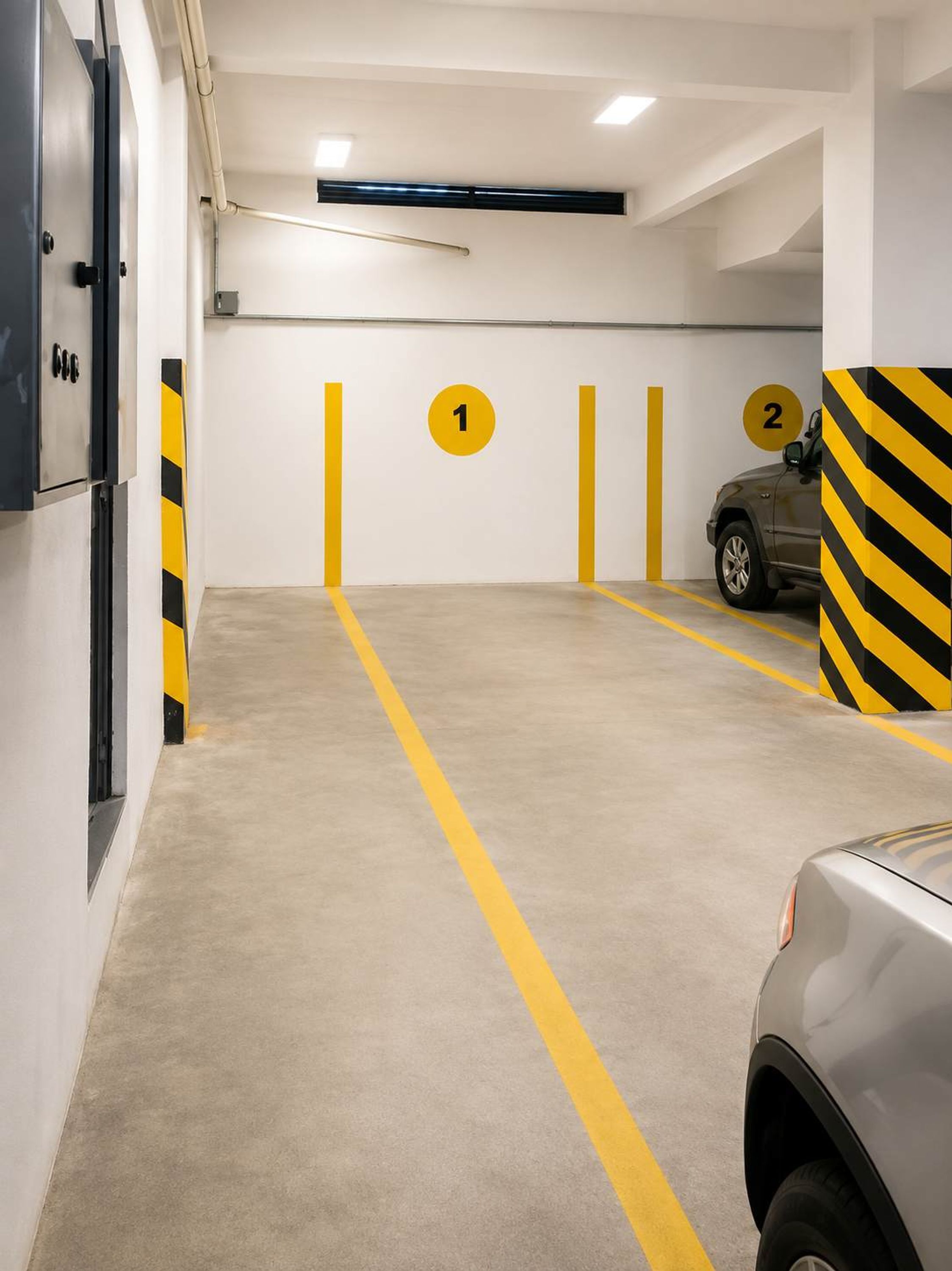A parking garage with numbered parking spaces, a car in space 2, and a fire extinguisher on the wall.