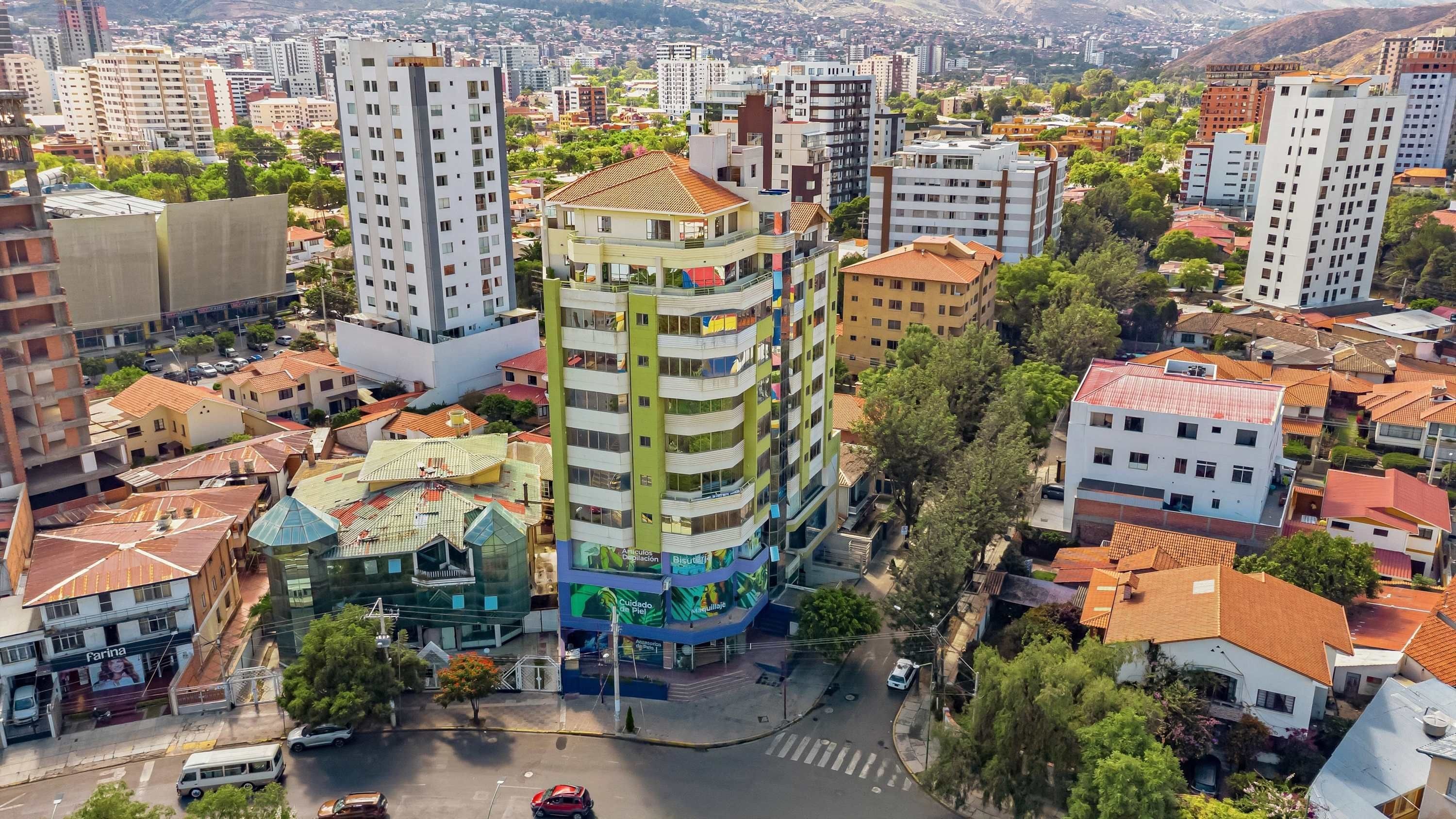 A multi-story building with a mix of residential and commercial spaces, surrounded by other buildings and greenery.