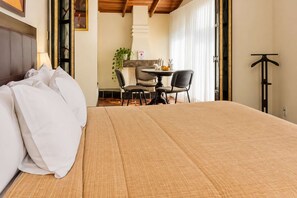 Una habitación de hotel con una cama, una mesa de comedor con sillas, una pequeña cocina y un perchero.