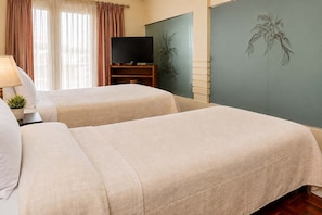 Habitación de hotel con dos camas, un televisor y una pared con un mural de plantas.