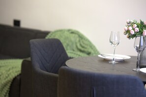 A dining area with a round table, two wine glasses, and a vase with flowers. - Cozy 1-bedroom apartment in charming Yerevan with AC (Yerevan)