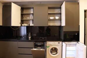 Une cuisine compacte équipée d’un lave-vaisselle, d’une machine à laver et d’un four à micro-ondes.