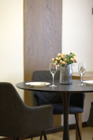 Une table à manger avec deux chaises, un vase rempli de fleurs et deux verres à vin.