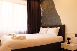 A hotel room with a bed, a nightstand, a lamp, and a large rock-like wall feature. - Cozy 1-bedroom apartment in charming Yerevan with AC (Yerevan)