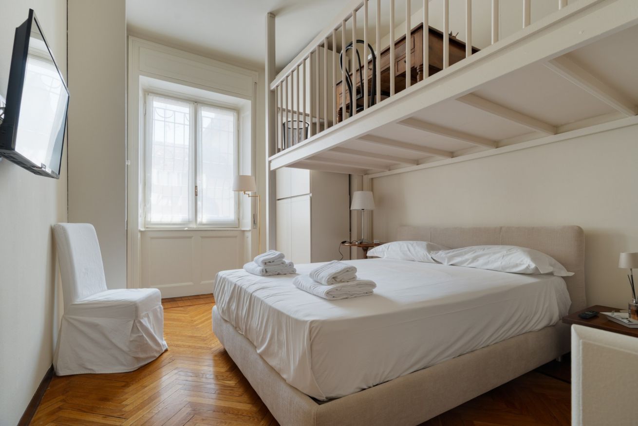 Una camera da letto con un letto, una sedia, una finestra e una scala.