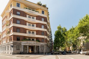 Un edificio residencial de varios pisos con balcones, base de piedra y cielo despejado.