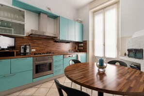 Una cocina moderna con armarios verde mar, una encimera de madera y una mesa de comedor redonda.