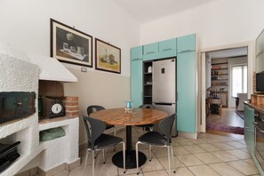 A kitchen with a round table, chairs, a refrigerator, and cabinets. - A spacious and charming 105 square-meter apartment, with vintage and classic-style décor, ideal for five people, located on the first floor (elevator available, though NOT suitable for people with disabilities) of a building near the lively, modern, and (Milan)