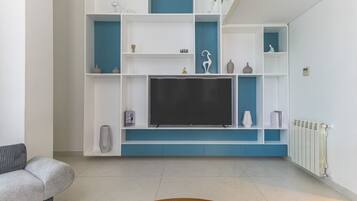 A modern living room with a flat-screen TV, built-in shelving, and a radiator.