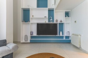 A modern living room with a flat-screen TV, built-in shelving, and a radiator. - Retro 67 (Beirut)