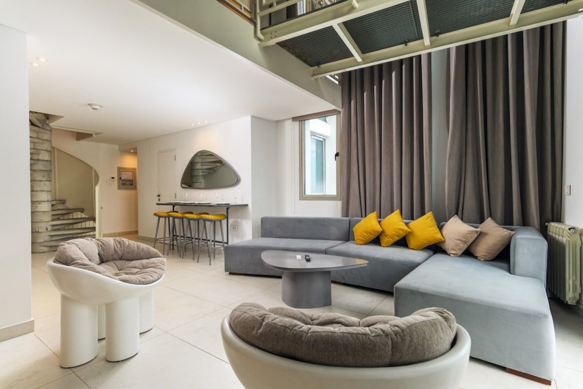 A modern living room with a grey sofa, a round coffee table, and a unique chair.