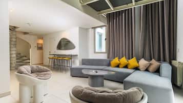 A modern living room with a grey sofa, a round coffee table, and a unique chair.