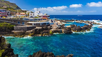 Un hotel junto a la costa con piscina, costa rocosa y mar azul cristalino.