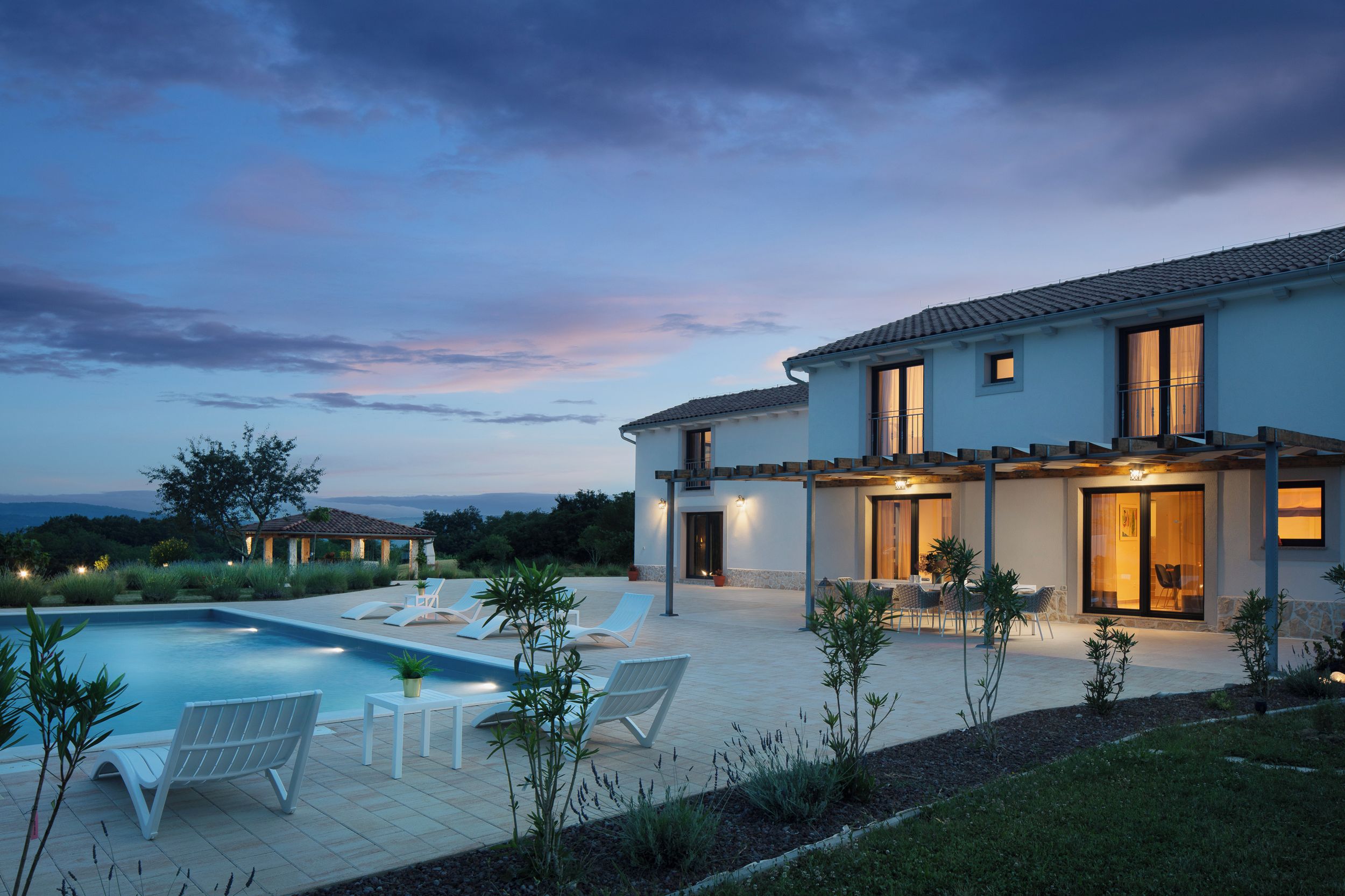 Une maison moderne à deux étages, dotée d’une piscine, d’un espace extérieur aménagé et offrant une vue sur le paysage.