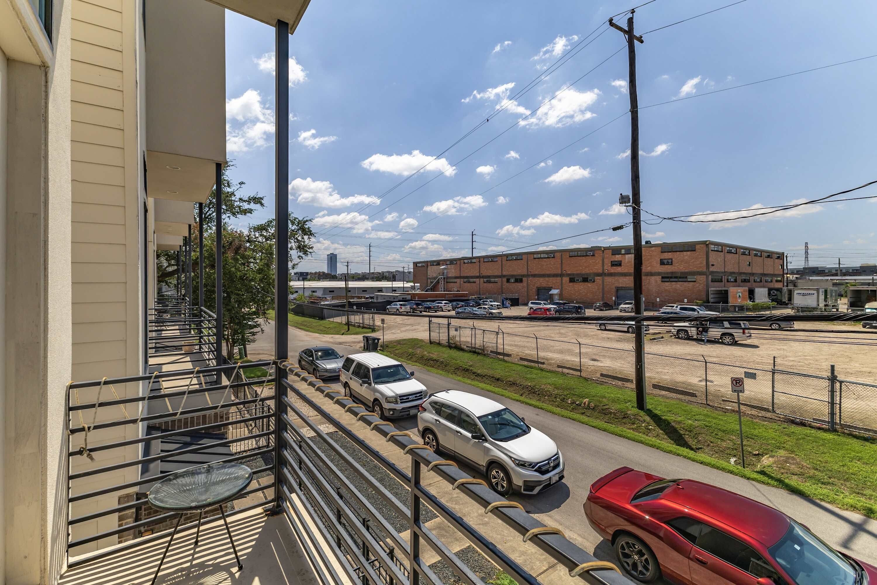 A balcony with a view of a parking lot and a building with multiple floors.