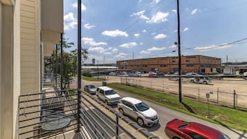 A balcony with a view of a parking lot and a building with multiple floors.