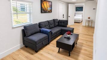 A modern living room with a sectional sofa, a coffee table, and a painting on the wall.