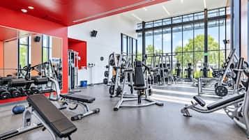 Una palestra moderna con diverse attrezzature per esercizi, ampie finestre e una parete di risalto rossa.