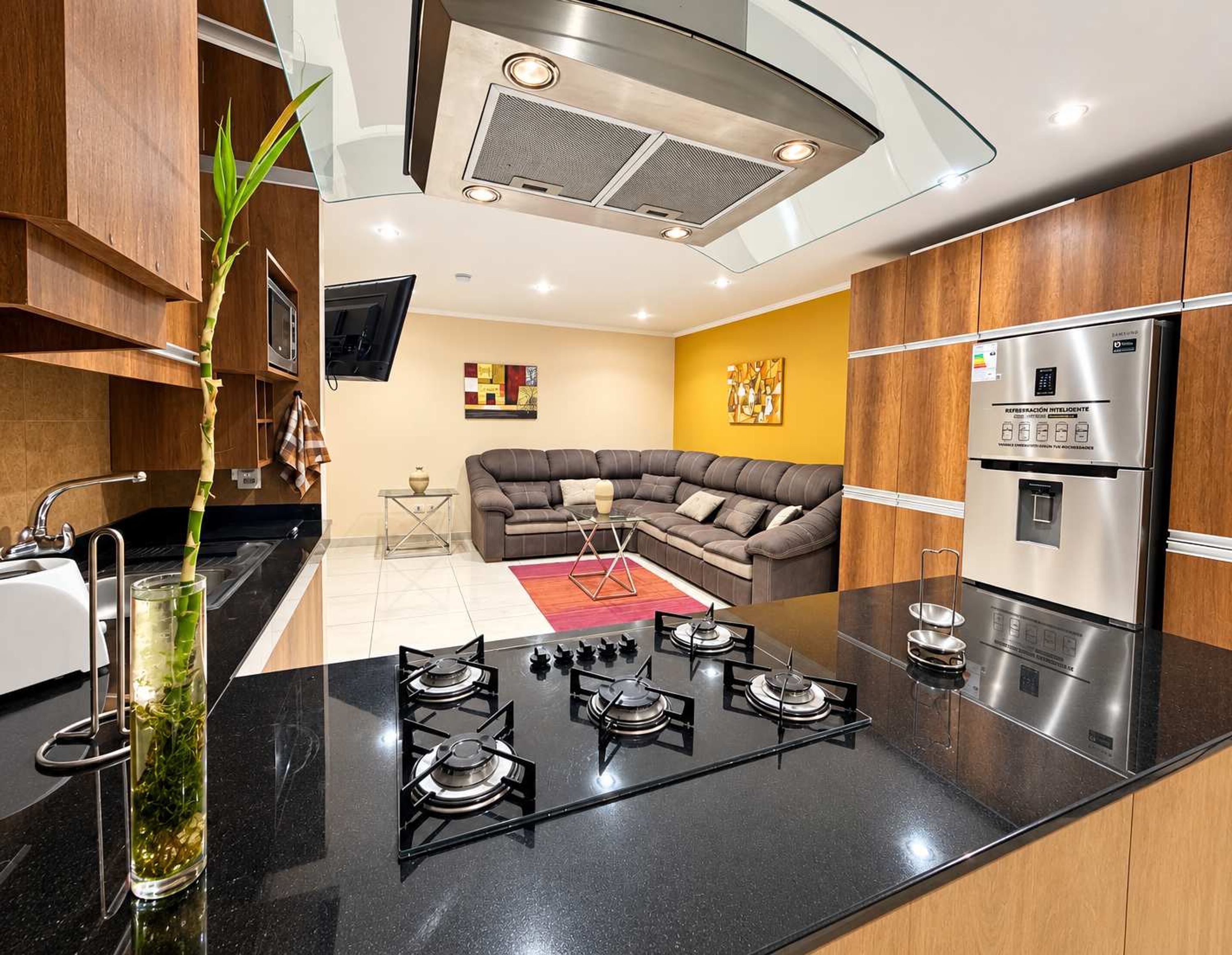 A modern kitchen with a central island, built-in appliances, and a dining area with a sofa.