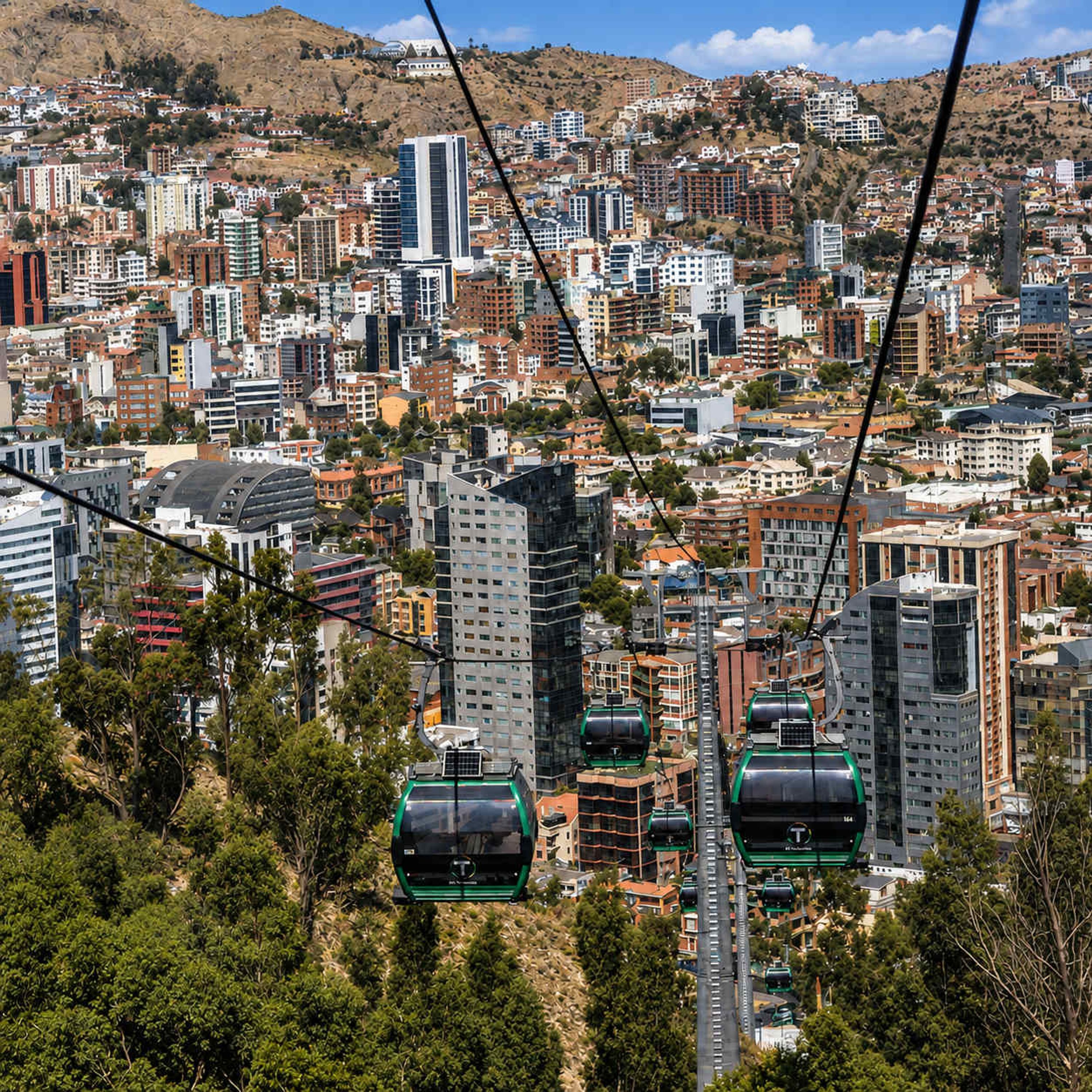 A cityscape with multiple high-rise buildings and a cable car system.