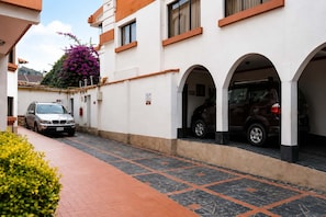 Un edificio con fachada blanca, varias ventanas y un camino de entrada pavimentado.