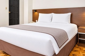 A hotel room with a bed, a bedside table, a phone, and a door. - Calacoto 2BR Apt King 2 Twins Sofa Bed (La Paz)