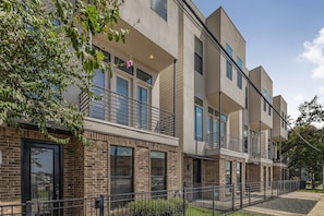 Edifício residencial de vários andares com fachada de tijolos, janelas amplas e varanda.