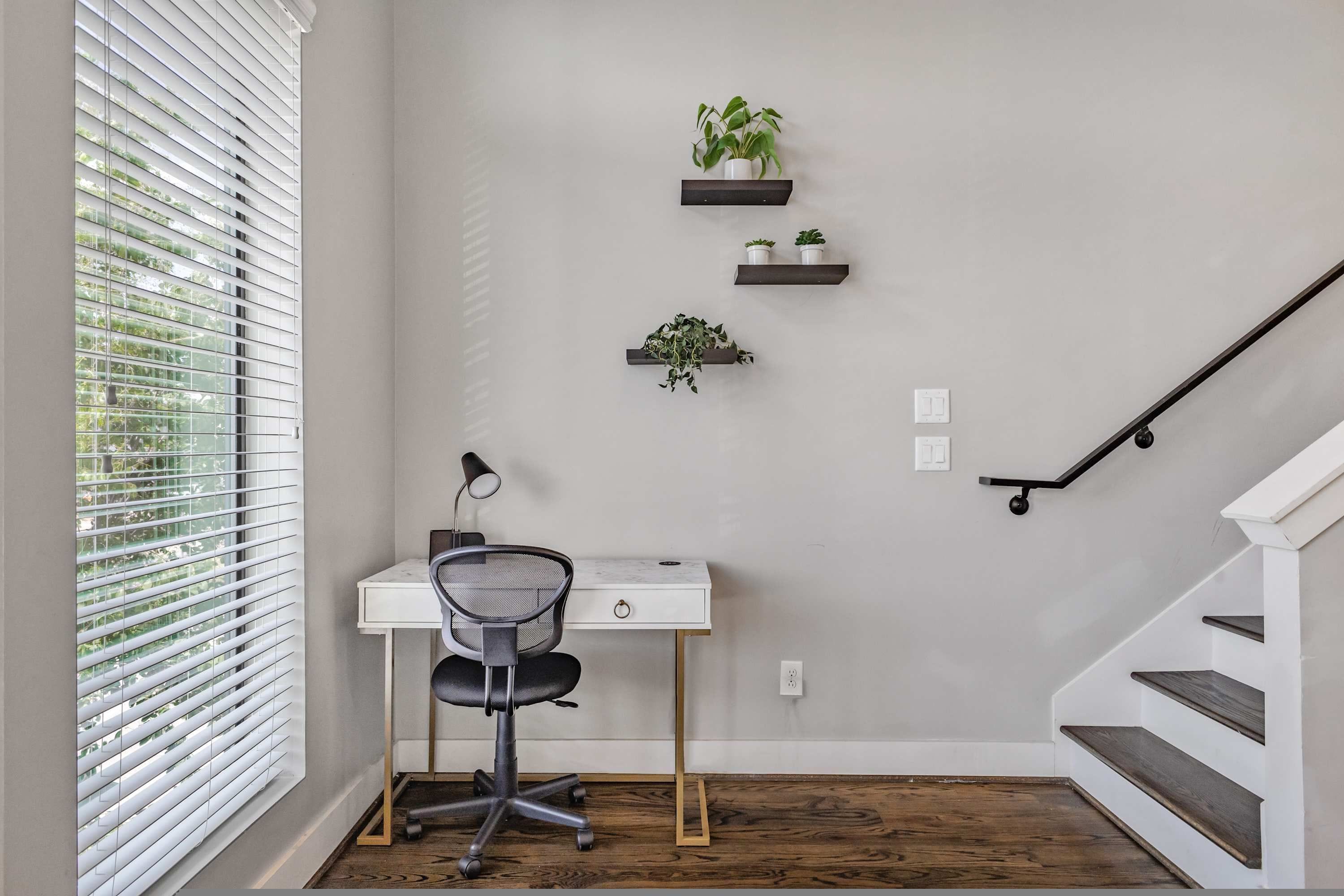 Ein Eckbüro mit Schreibtisch, Stuhl und zwei an der Wand befestigten Regalen mit Pflanzen.