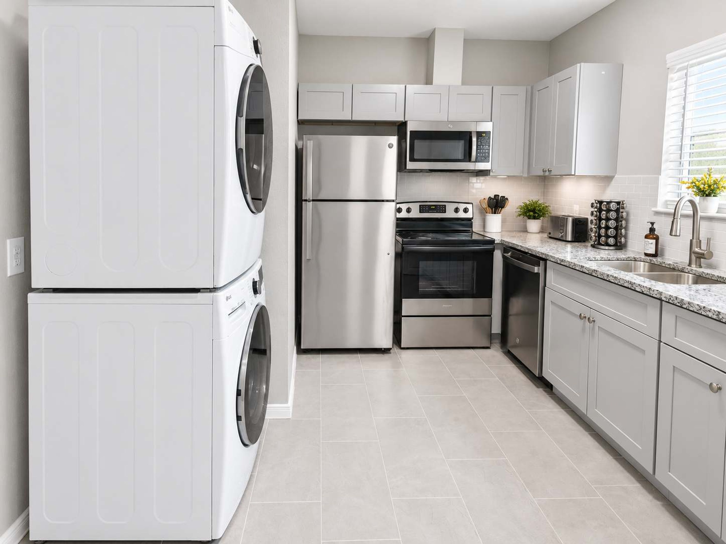 A modern kitchen with stainless steel appliances, including a washing machine, refrigerator, microwave, oven, and dishwasher.