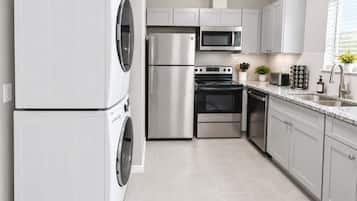 A modern kitchen with stainless steel appliances, including a washing machine, refrigerator, microwave, oven, and dishwasher.